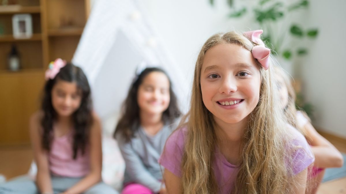 Joyful girls with pink ribbons enjoying together indoors.